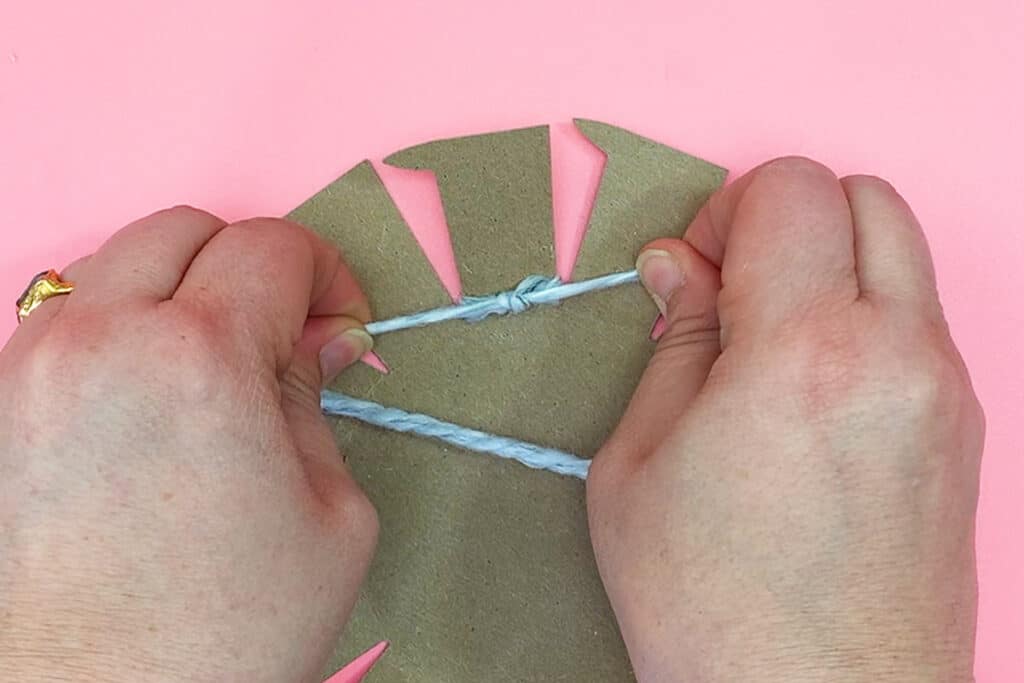 Hands tying knot onto cardboard extension.