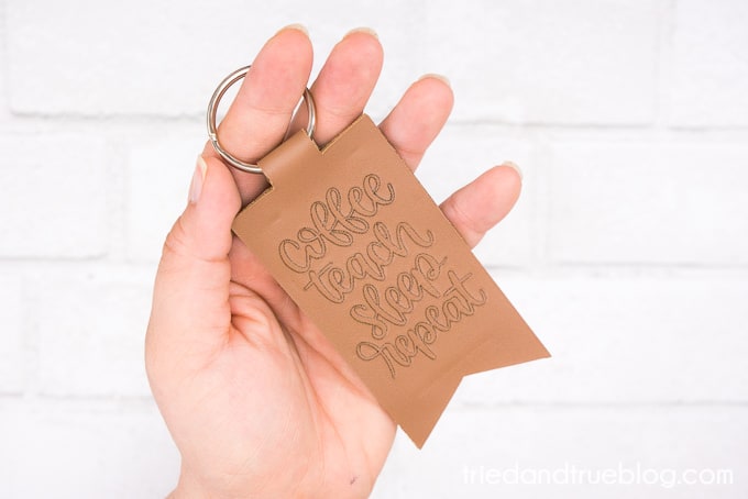 Hand holding a debossed leather keychain that says 