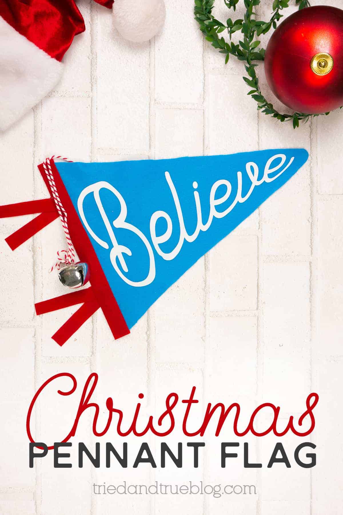 Blue Christmas Felt Pennant Flag on a white brick background with various Christmas supplies.