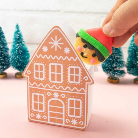 Hand inserting a elf lollypop into a Gingerbread Gift Box.