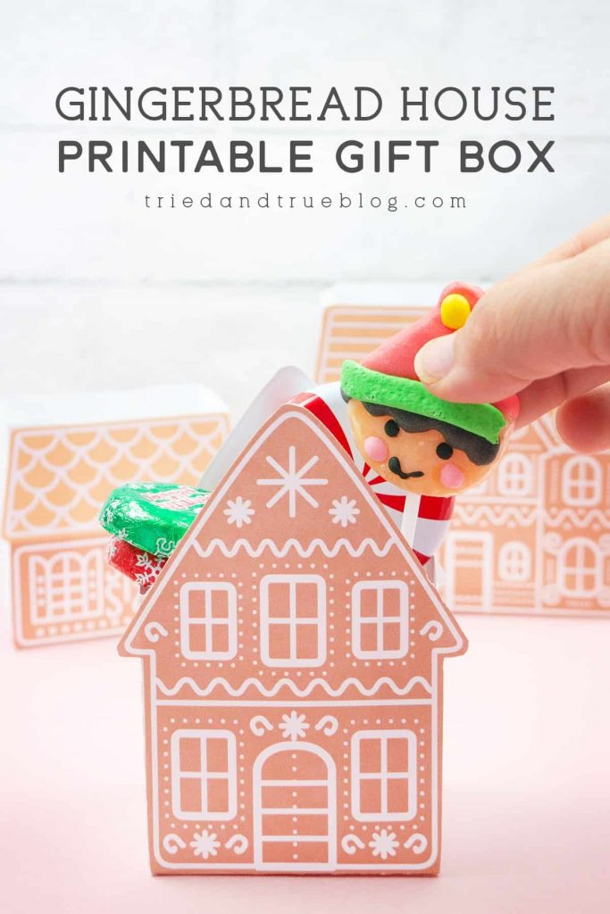 Hand inserting a lollypop into a Gingerbread House Gift Box
