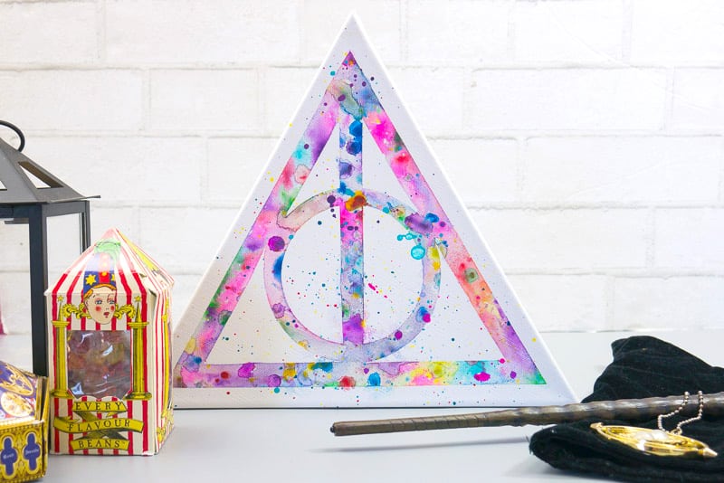 Triangular canvas with Harry Potter Deathly Hallows watercolor art surrounded by other memorabilia. 