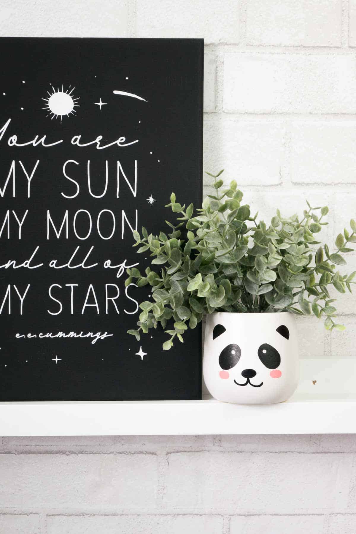 White ceramic planter with painted panda face on a ledge.