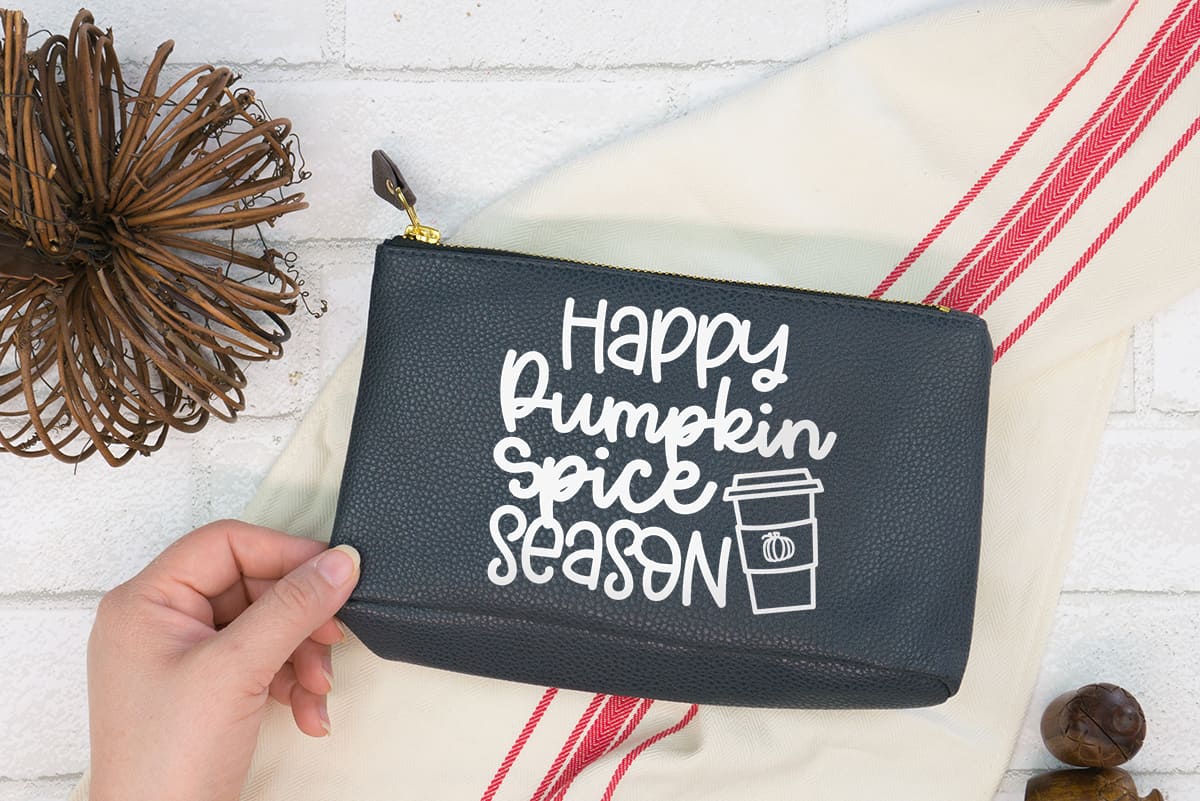 Hand holding black make-up bag with the Pumpkin Spice Season Free SVG 