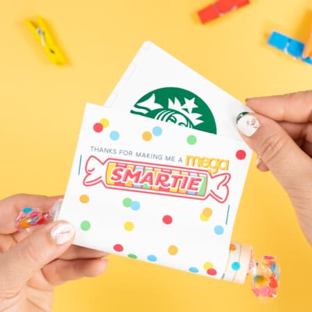 Hand holding smartie easy teacher appreciation gift on yellow background with Starbucks gift card