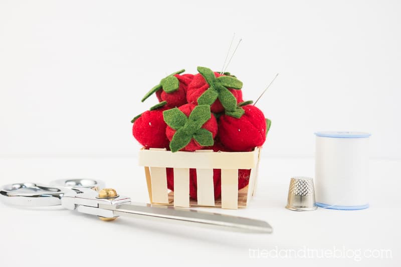 Felt strawberries in a mini berry basket with needles sticking out.