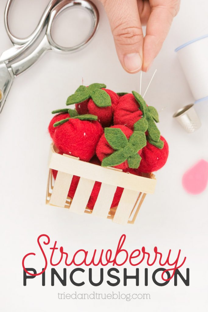 Close up image of hand placing needle into a Strawberry Pincushion.