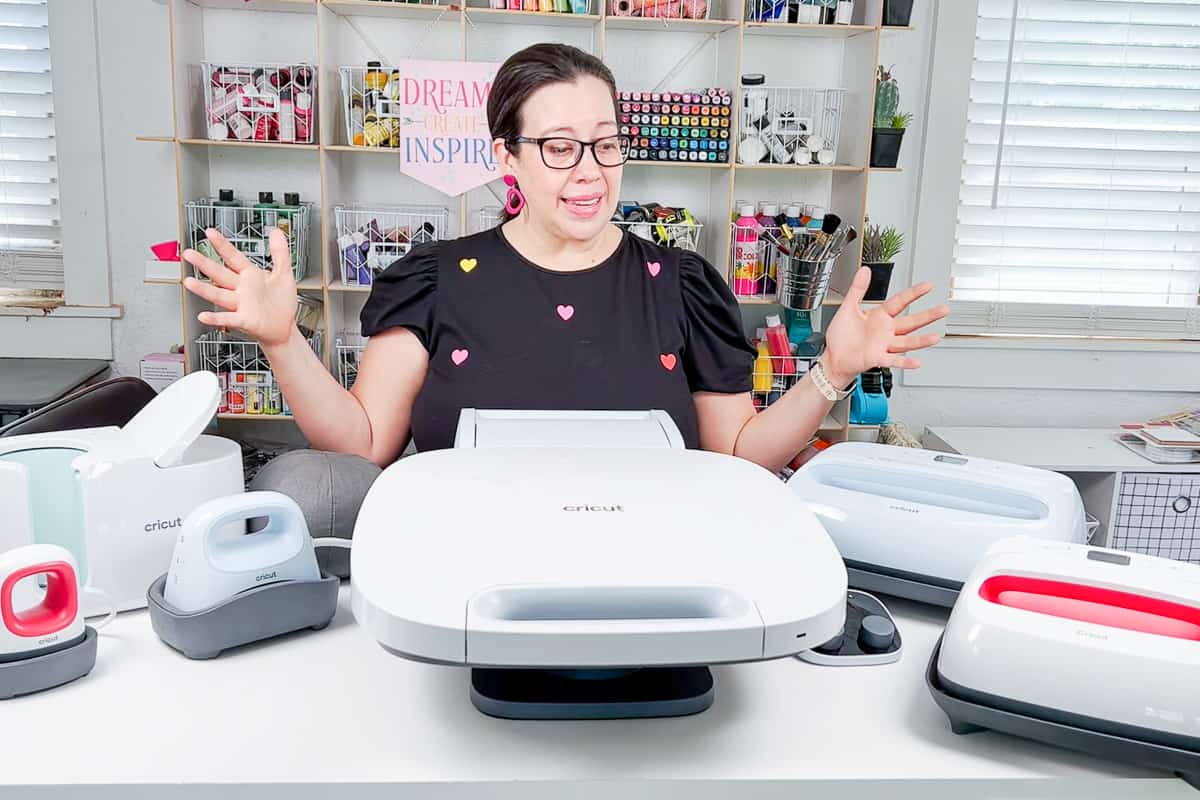 Woman standing in front of various Cricut Heat Presses with hands upraised.
